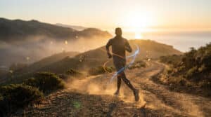 Un coureur de fond en plein effort sur un sentier montagneux au coucher du soleil avec des effets lumineux dynamiques.